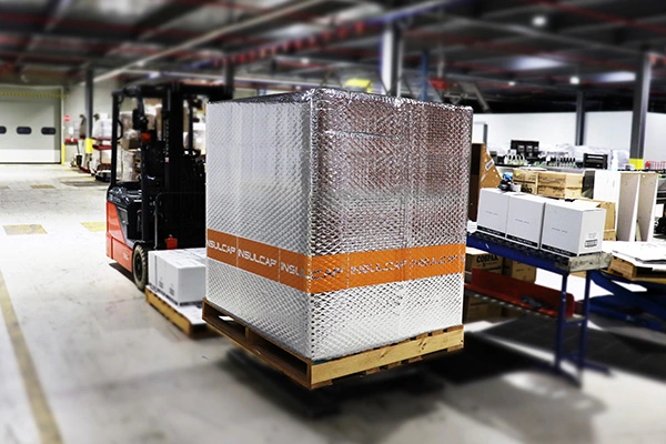 A forklift carrying a pallet wrapped in InsulCap reflective thermal insulation.